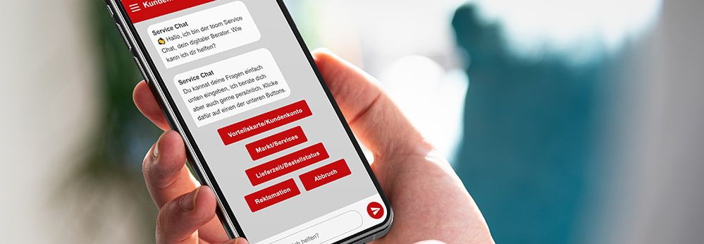 Person hält Smartphone mit geöffnetem Chatbot in der Hand